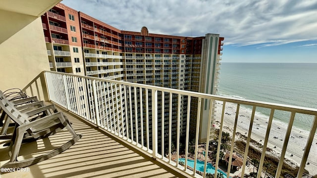 balcony with a water view and a view of the beach