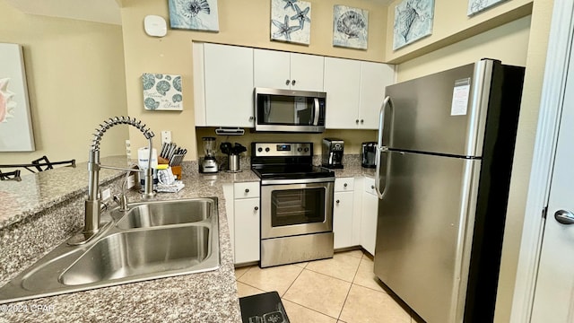 kitchen with white cabinets, sink, light tile patterned floors, and stainless steel appliances