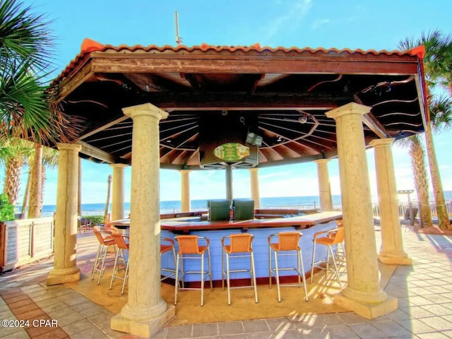 view of patio with a gazebo, a water view, and a bar