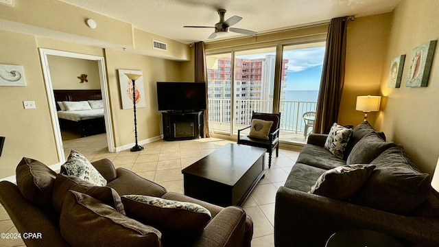 living room with a textured ceiling, ceiling fan, light tile patterned floors, and a fireplace