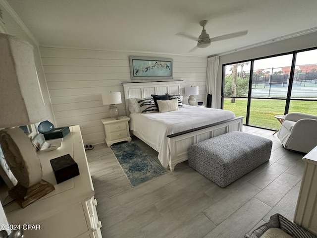 bedroom featuring wooden walls, light wood-type flooring, ceiling fan, ornamental molding, and access to exterior