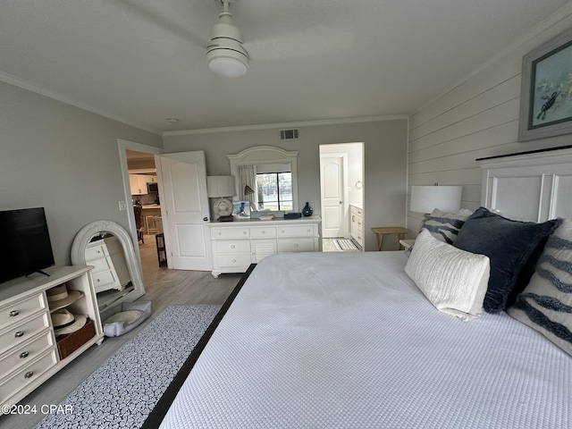 bedroom featuring ensuite bath, wooden walls, dark hardwood / wood-style floors, and ornamental molding