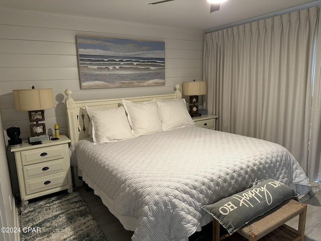 bedroom with ceiling fan and wooden walls