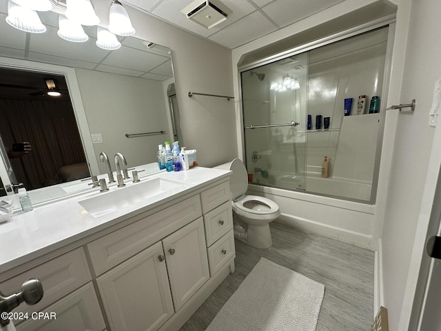 full bathroom with a paneled ceiling, shower / bath combination with glass door, vanity, and toilet