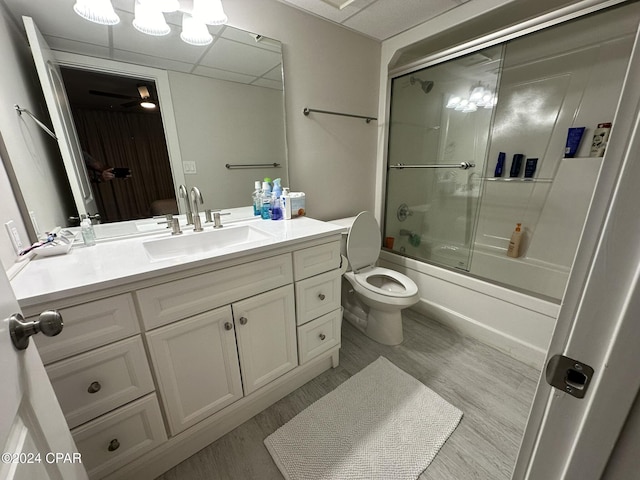 full bathroom featuring toilet, a paneled ceiling, vanity, bath / shower combo with glass door, and hardwood / wood-style flooring