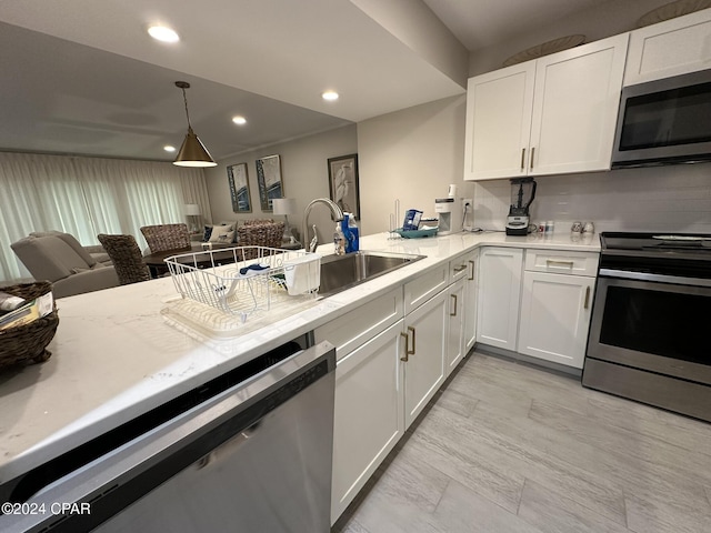 kitchen featuring sink, appliances with stainless steel finishes, hanging light fixtures, and white cabinetry