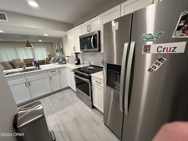 kitchen with sink, stainless steel appliances, white cabinetry, and kitchen peninsula