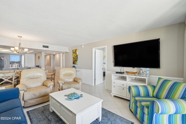 living room with a textured ceiling, an inviting chandelier, and light tile patterned flooring