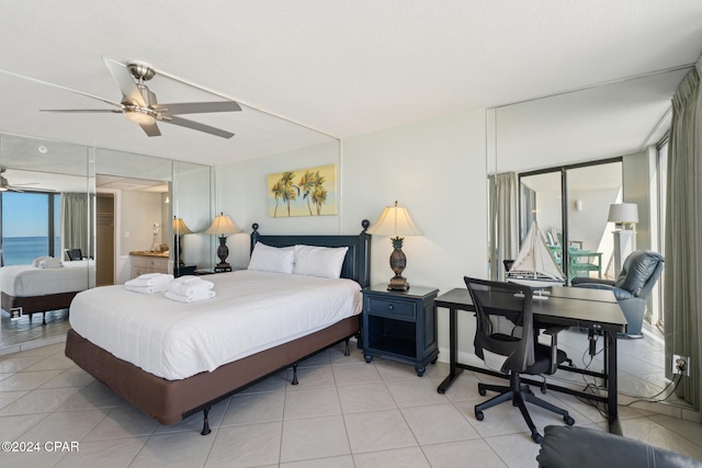 bedroom with multiple windows, ceiling fan, a water view, and light tile patterned flooring