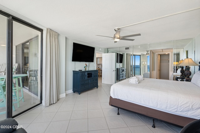 bedroom with ceiling fan, expansive windows, and light tile patterned floors