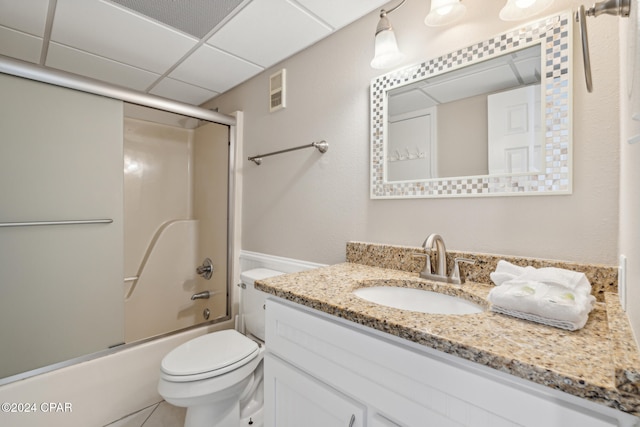 full bathroom with a drop ceiling, toilet, enclosed tub / shower combo, and vanity