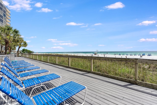 wooden deck with a water view and a view of the beach