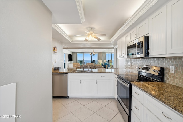 kitchen featuring a raised ceiling, stainless steel appliances, white cabinetry, and sink