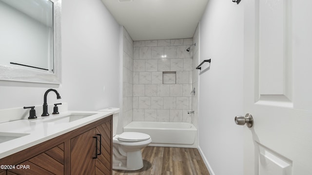 full bathroom featuring vanity, tiled shower / bath, hardwood / wood-style flooring, and toilet