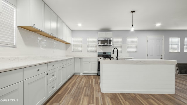 kitchen featuring hanging light fixtures, plenty of natural light, stainless steel appliances, and white cabinets