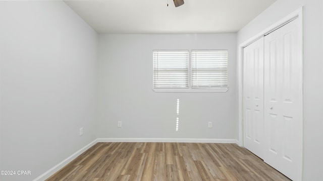 unfurnished bedroom with wood-type flooring, a closet, and ceiling fan