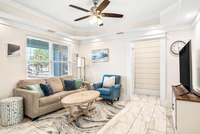 living room featuring a raised ceiling and ceiling fan