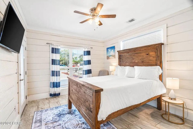 bedroom with ceiling fan, light hardwood / wood-style floors, and wood walls