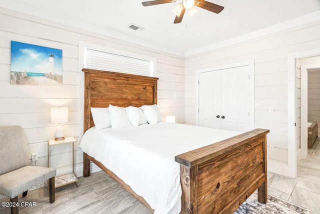 bedroom featuring ceiling fan, wood walls, and a closet