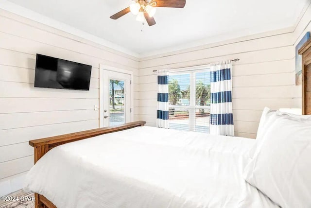 bedroom featuring ceiling fan, access to exterior, and wooden walls