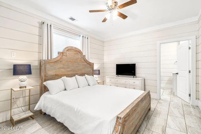 bedroom with ceiling fan and wooden walls