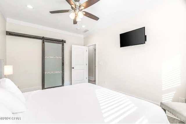 unfurnished bedroom with a barn door and ceiling fan