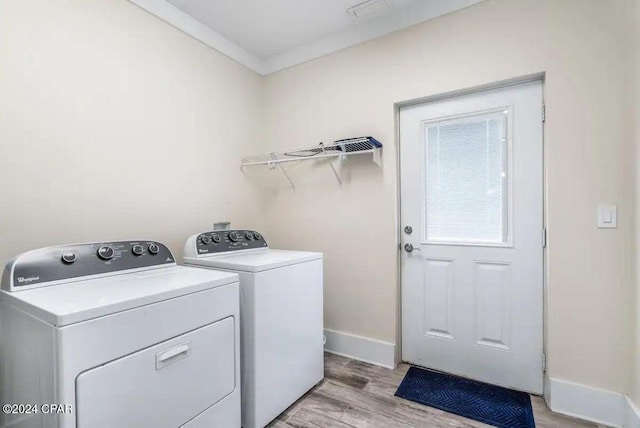 clothes washing area with light hardwood / wood-style floors and washing machine and clothes dryer