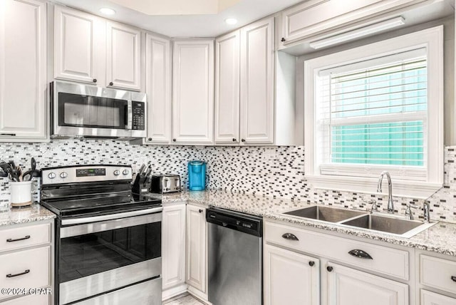 kitchen with tasteful backsplash, white cabinetry, sink, and stainless steel appliances