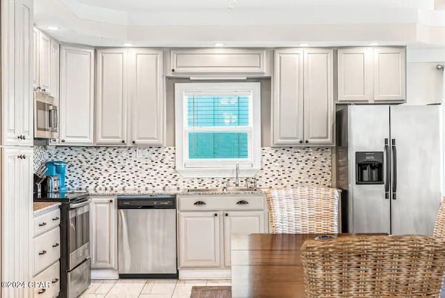 kitchen with backsplash, light stone counters, sink, and stainless steel appliances