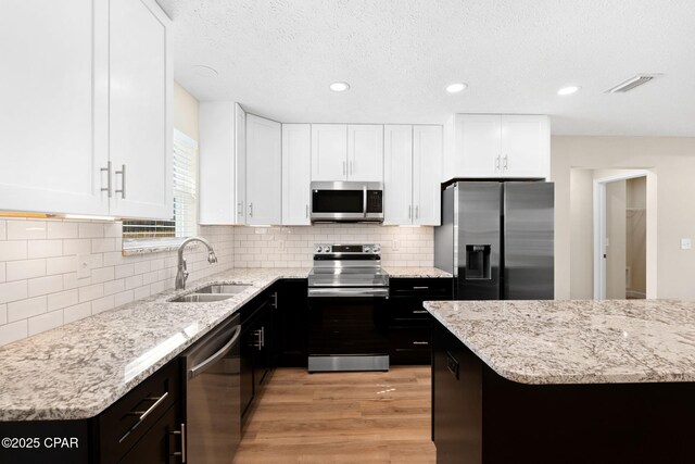 kitchen featuring stainless steel appliances, white cabinetry, sink, and light hardwood / wood-style floors