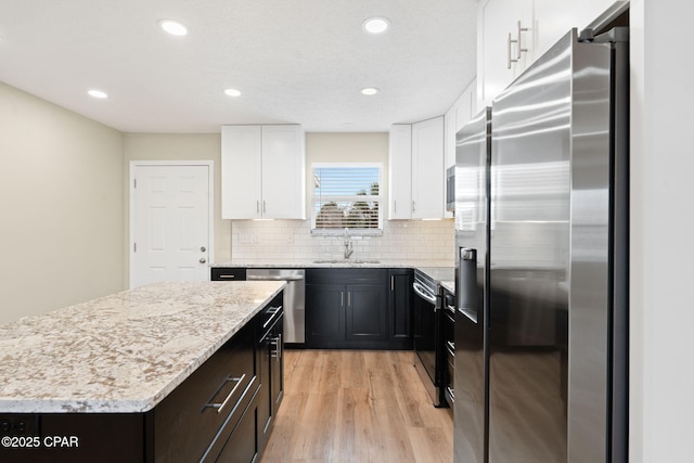 kitchen with sink, white cabinetry, tasteful backsplash, a kitchen island, and stainless steel appliances