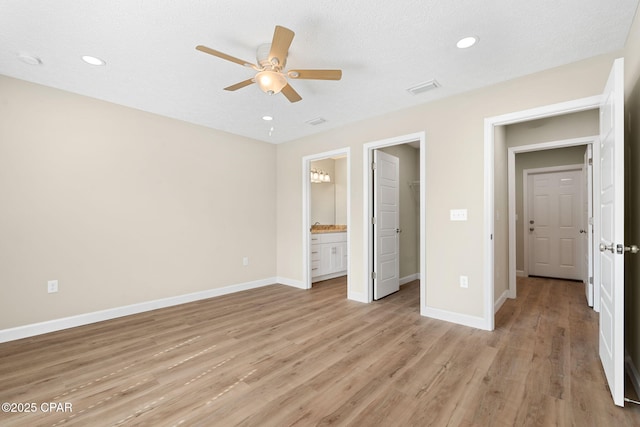 unfurnished bedroom featuring connected bathroom, a spacious closet, a textured ceiling, ceiling fan, and light hardwood / wood-style floors