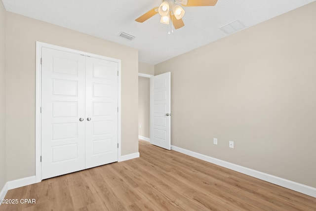 unfurnished bedroom with a textured ceiling, a closet, ceiling fan, and light wood-type flooring