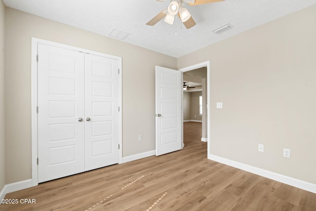 unfurnished bedroom featuring a textured ceiling, light hardwood / wood-style flooring, a closet, and ceiling fan