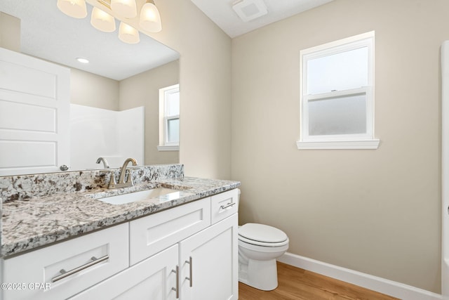 bathroom featuring hardwood / wood-style flooring, vanity, a shower, and toilet