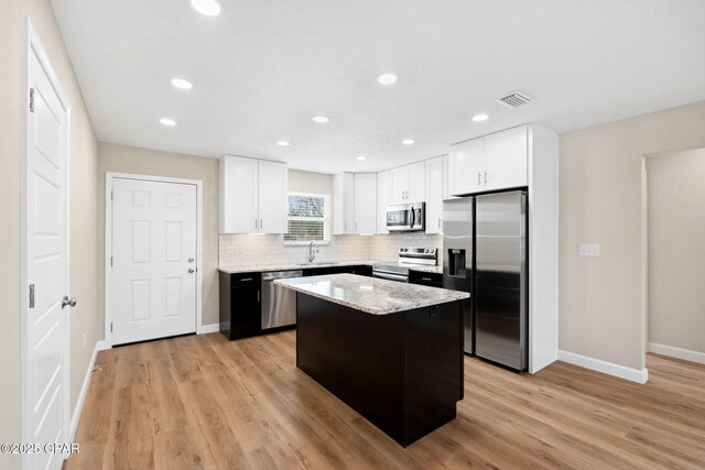 kitchen featuring backsplash, stainless steel appliances, a center island, and white cabinets