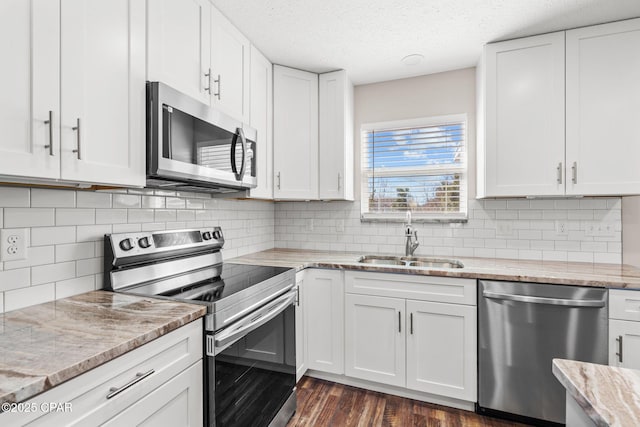 kitchen featuring appliances with stainless steel finishes, white cabinets, and a sink