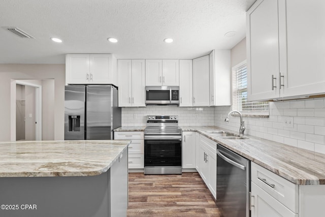 kitchen featuring appliances with stainless steel finishes, white cabinetry, and a sink