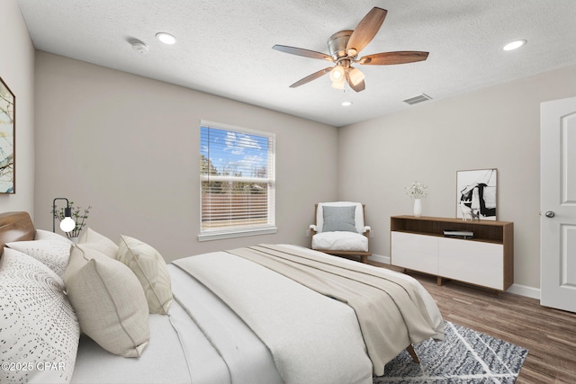 bedroom with dark wood-style floors, visible vents, and a textured ceiling