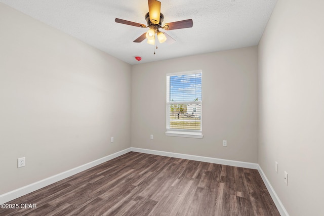 empty room featuring a textured ceiling, ceiling fan, dark wood-style flooring, and baseboards