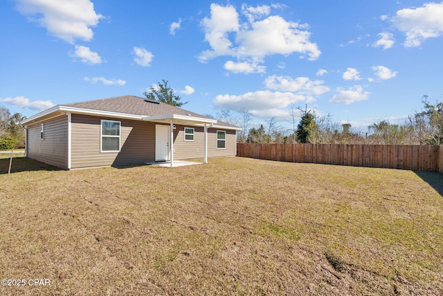 rear view of property featuring a yard, a patio area, and fence