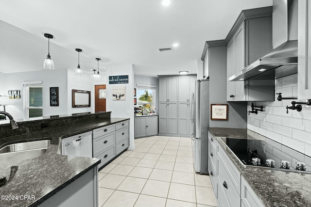 kitchen with wall chimney exhaust hood, decorative light fixtures, stainless steel appliances, sink, and gray cabinetry