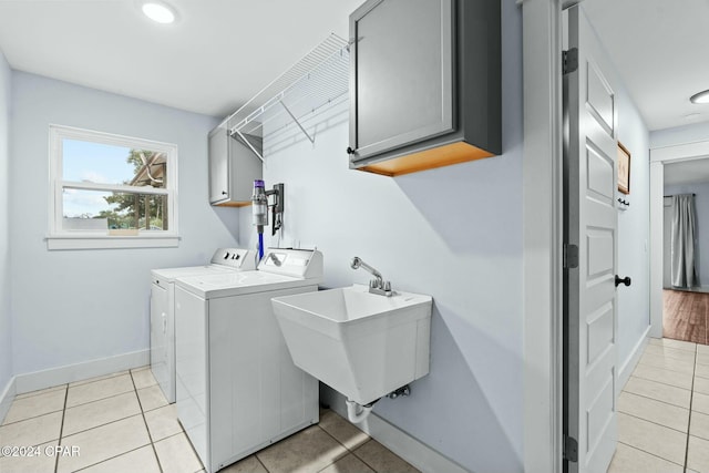 laundry room featuring light tile patterned floors, sink, washing machine and clothes dryer, and cabinets