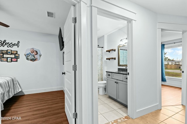 bedroom with ensuite bath, sink, and light tile patterned flooring