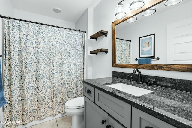 bathroom with toilet, vanity, and tile patterned floors