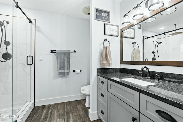 bathroom with toilet, a shower with shower door, wood-type flooring, and vanity