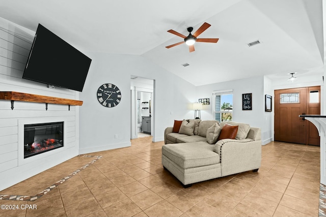 tiled living room featuring ceiling fan, vaulted ceiling, and a large fireplace