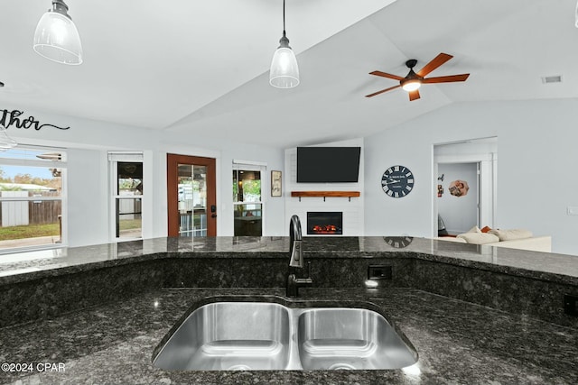 kitchen with sink, pendant lighting, dark stone countertops, and vaulted ceiling