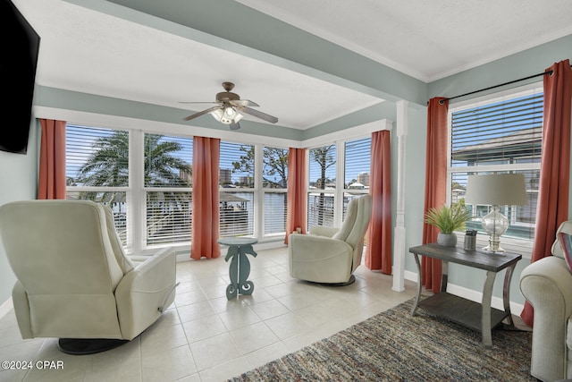 living area with ceiling fan, crown molding, and light tile patterned flooring