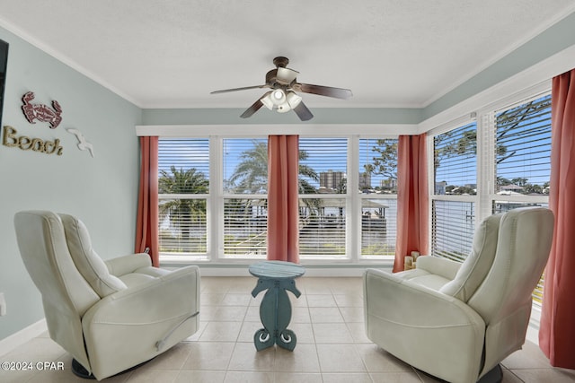 living area with a textured ceiling, ceiling fan, light tile patterned flooring, and crown molding